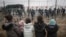 Migrant children stand in front of a barbed wire fence and Polish servicemen on the Belarusian side of Poland's Kuznitsa checkpoint  on November 17, 2021, as reports first surfaced of the migrants' withdrawal from the area, under Belarusian forces' supervision. 