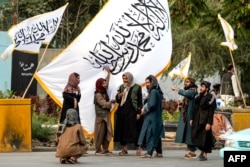 Талибы стоят у флагов Талибана накануне четвертой годовщины прихода Талибана к власти в 2021 году в Кабуле, 14 августа 2025 года. Фото AFP