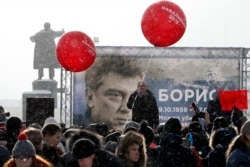 People in St. Petersburg participate in a 2018 memorial event for Boris Nemtsov, seen on the billboard.